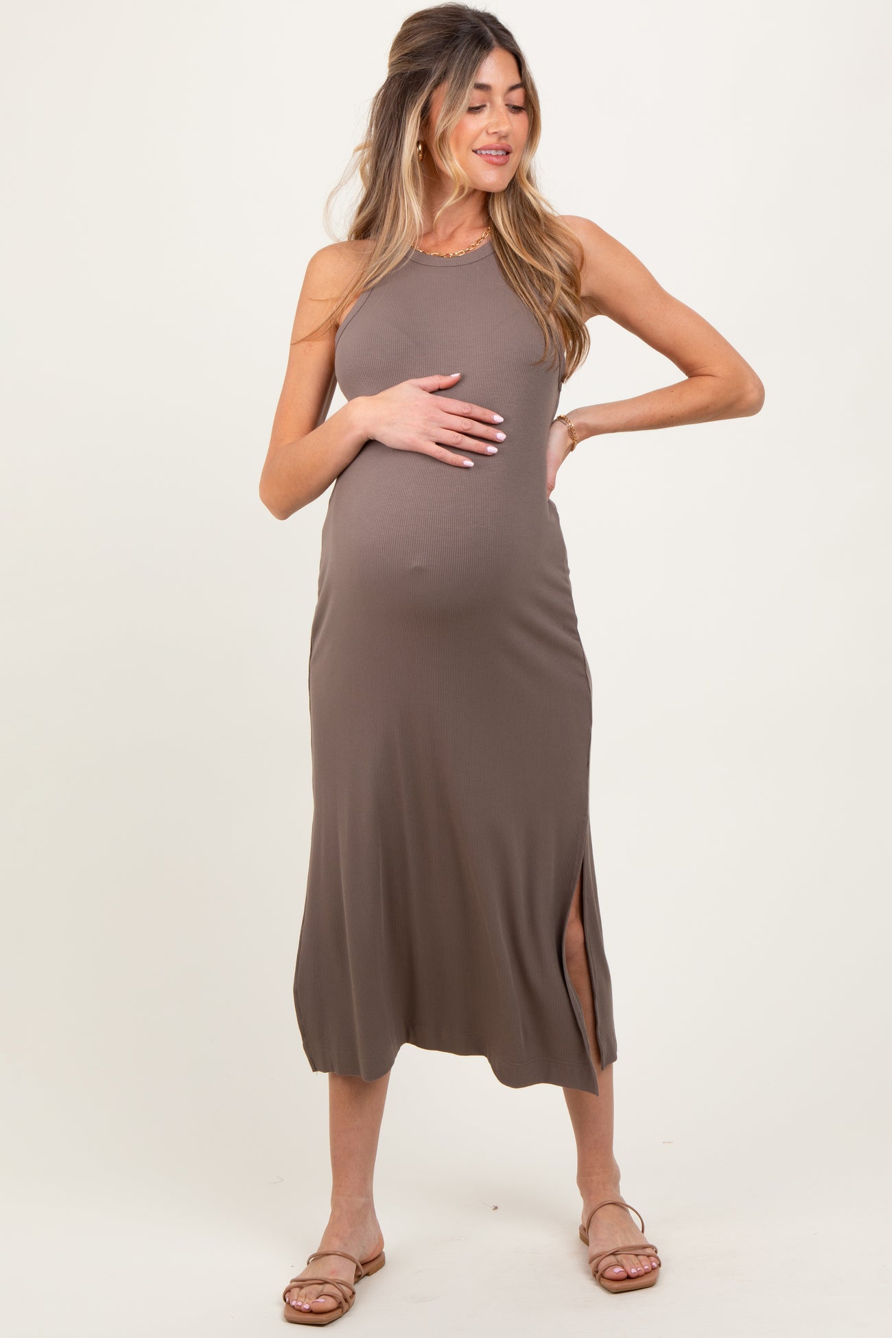 woman wearing a taupe maternity midi dress with side slit and holding her baby bump