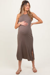 woman wearing a taupe maternity midi dress with side slit and holding her baby bump