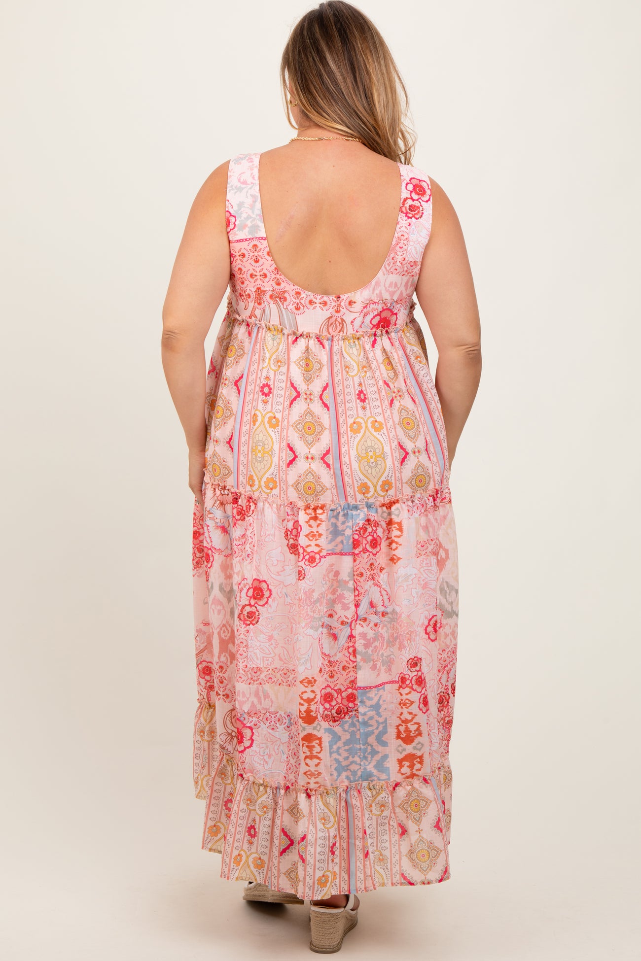 woman wearing a colorful patterned maternity plus maxi dress with a tiered design and a scoop back