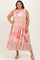 woman wearing a colorful plus size maxi dress with a tiered design and floral patterns, standing with one hand on her hip