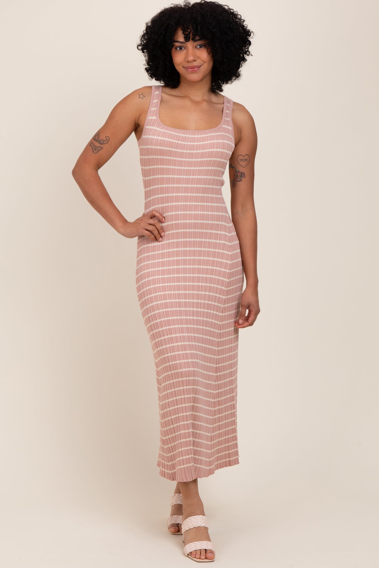 woman wearing a mauve striped sleeveless midi dress with a fitted silhouette and standing on a neutral background