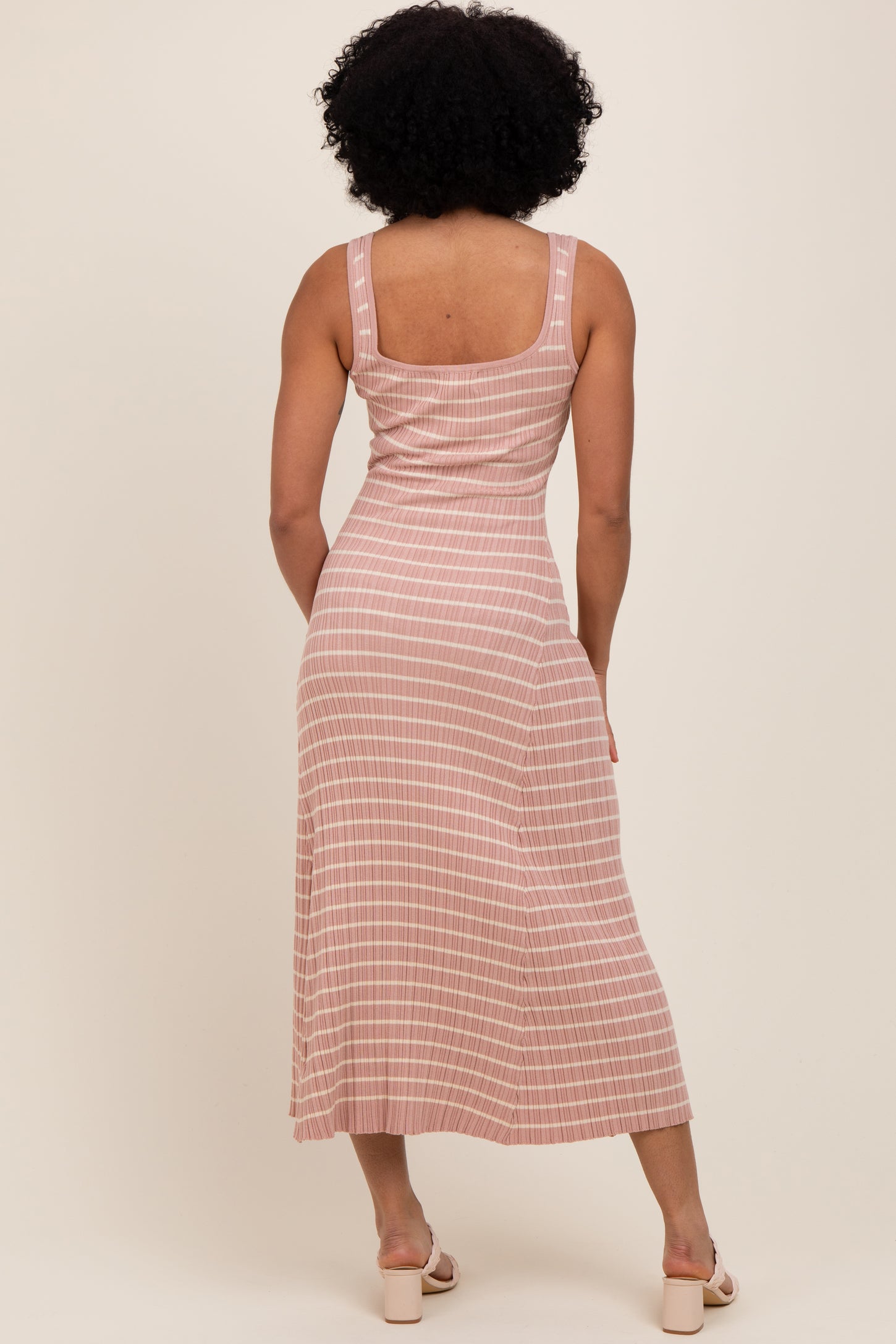 woman wearing a blush pink striped midi dress, showing the back with a fitted silhouette and squared neckline