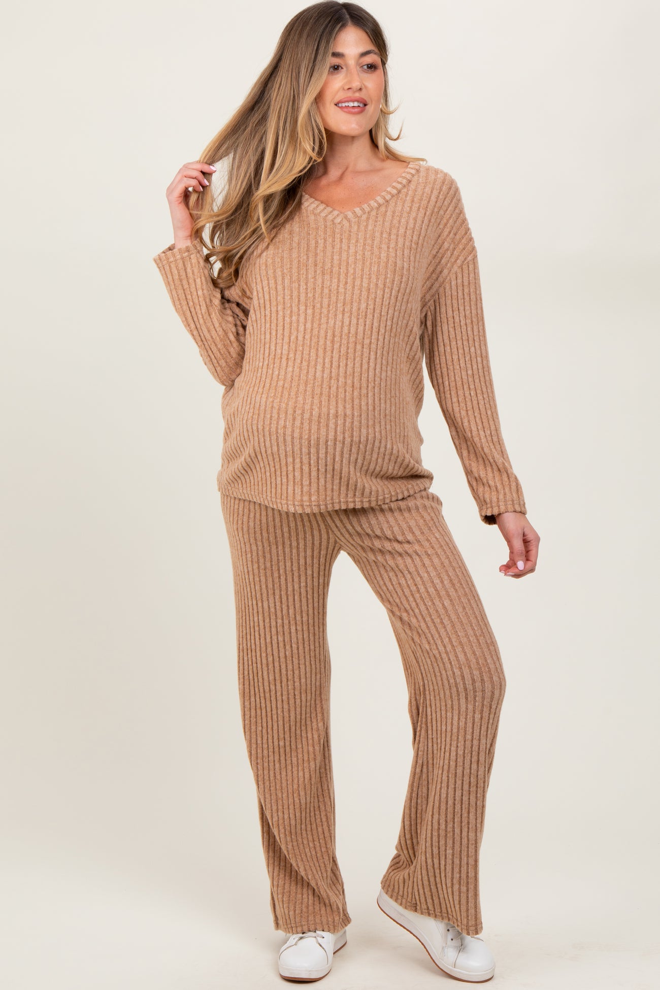 woman wearing a light brown ribbed maternity loungewear set with a v-neck top and pants, showcasing a visible baby bump