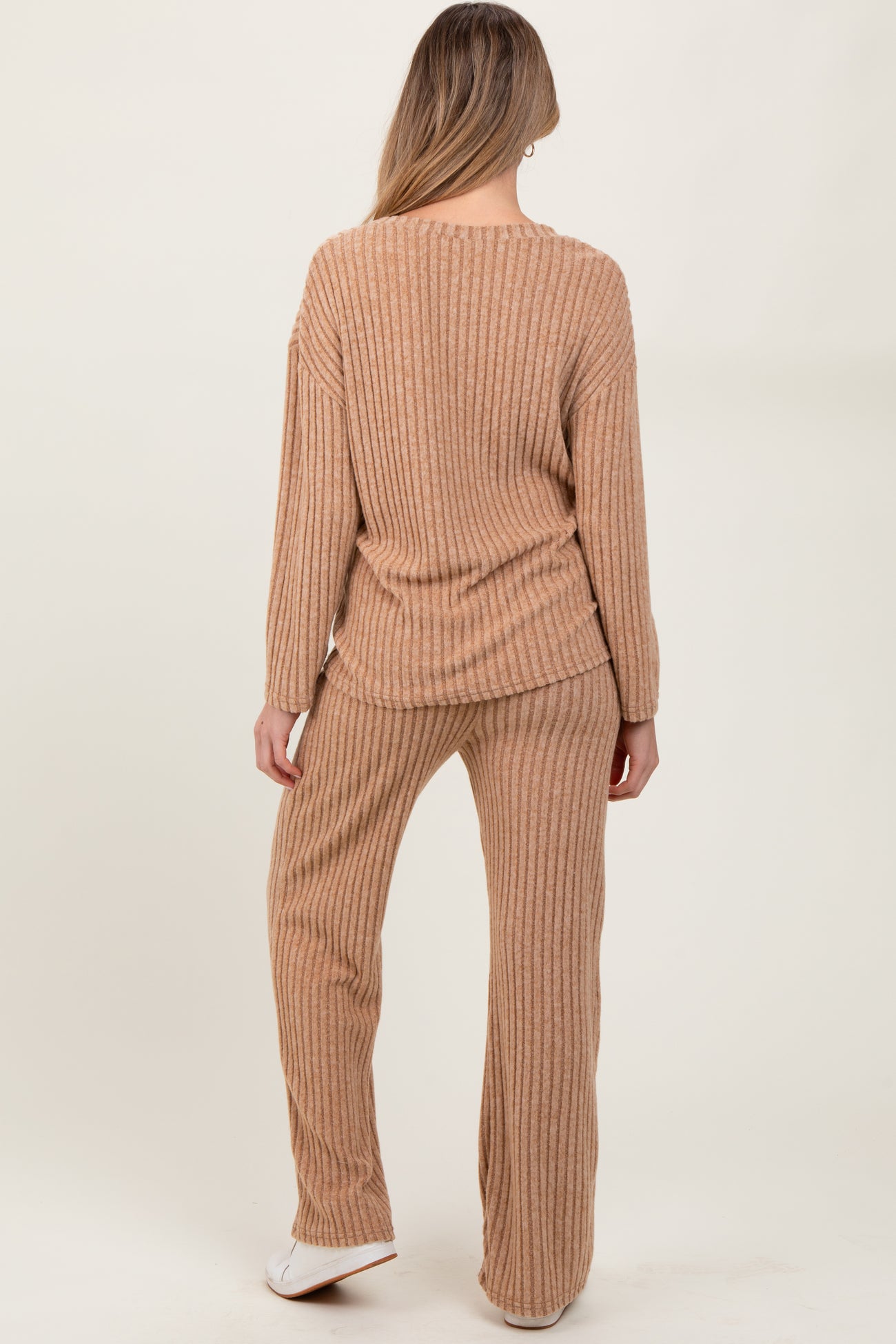 woman wearing a beige ribbed maternity loungewear set consisting of a long sleeve top and matching pants