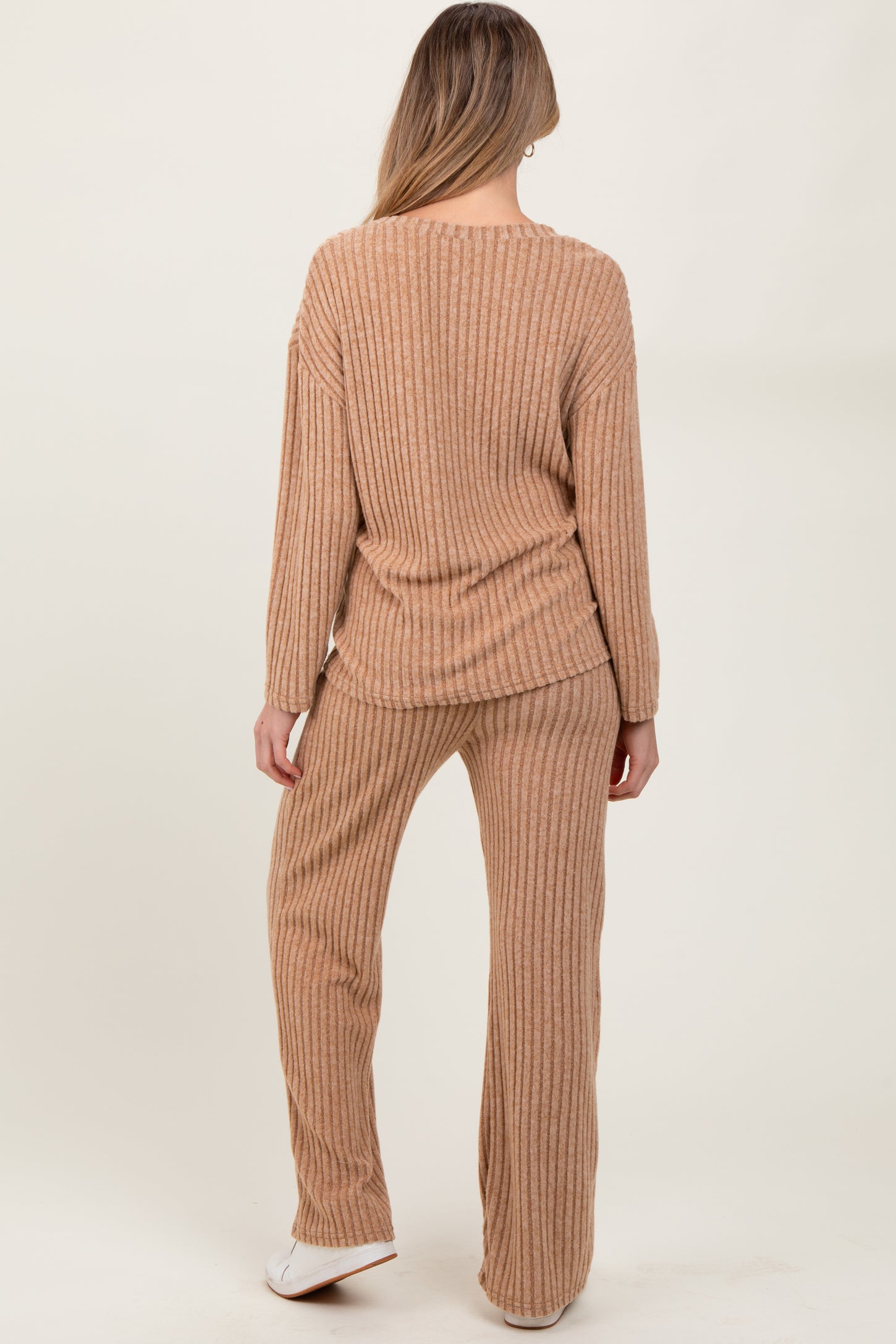 woman wearing a beige ribbed maternity loungewear set consisting of a long sleeve top and matching pants
