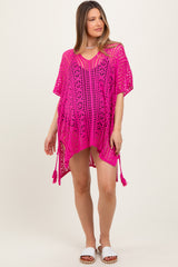 woman wearing a bright pink crochet maternity cover-up with side tassels and a loose fit, showcasing a baby bump