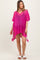 woman wearing a bright pink crochet maternity cover-up with side tassels and a loose fit, showcasing a baby bump