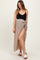 woman wearing a black ribbed maternity tank top and a beige wrap maxi skirt with a side slit and tied waist detail