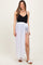 woman wearing a black maternity swim top and a white maxi cover-up with a side slit and tie waist detail