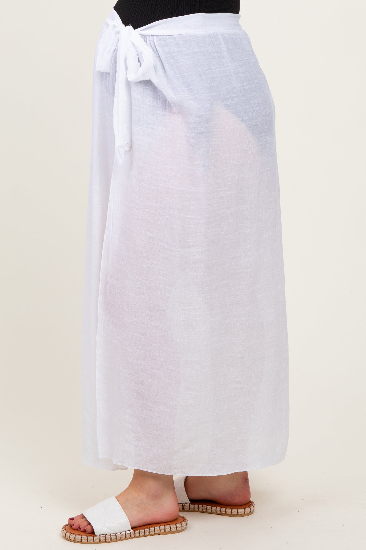 woman wearing a sheer white maternity cover-up skirt tied at the waist, displaying a casual summer style