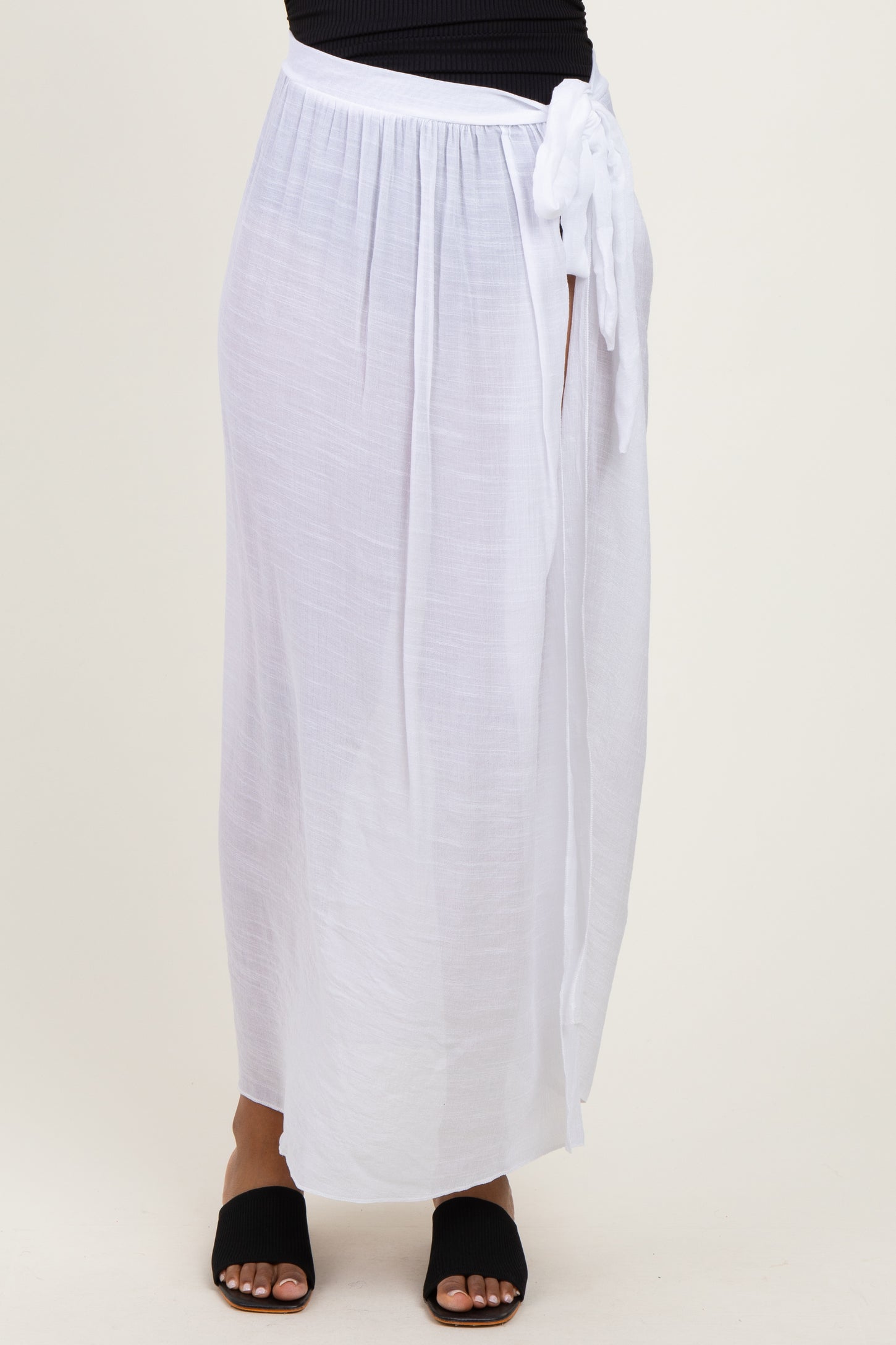 woman wearing a white maxi skirt with a side slit and a waist tie detail