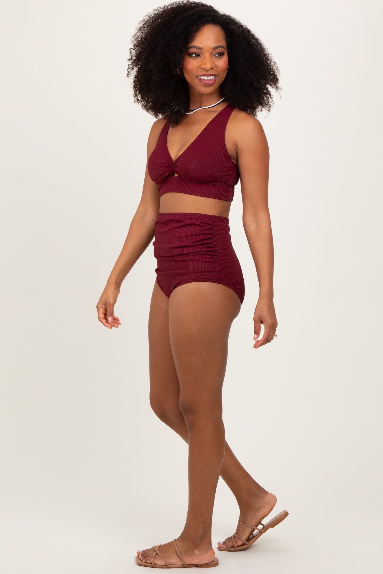 woman wearing a burgundy ribbed two-piece swimsuit with a knotted crop top and high-waisted bottoms