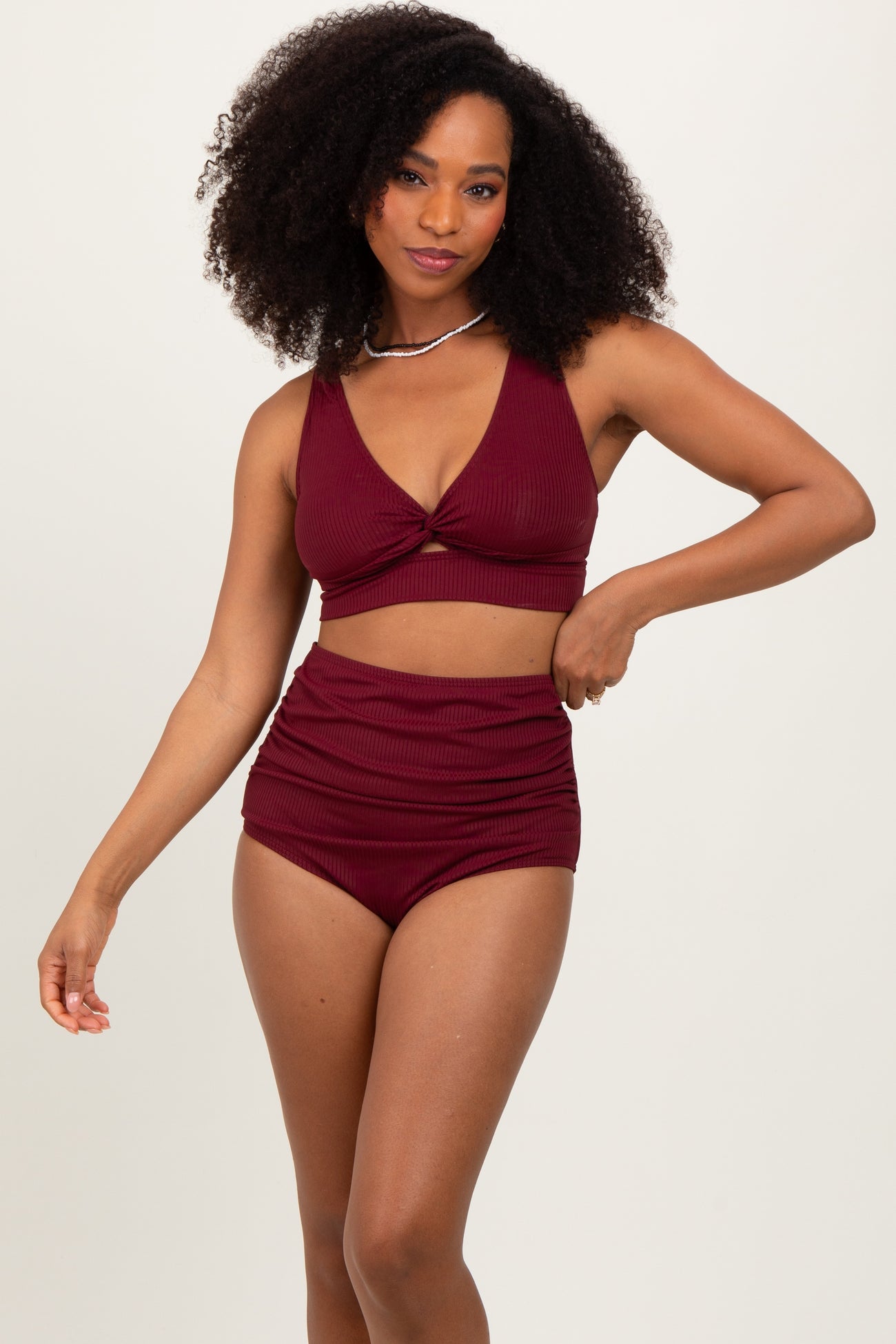 woman wearing a burgundy ribbed bikini set with a twist front top and high-waisted bottom