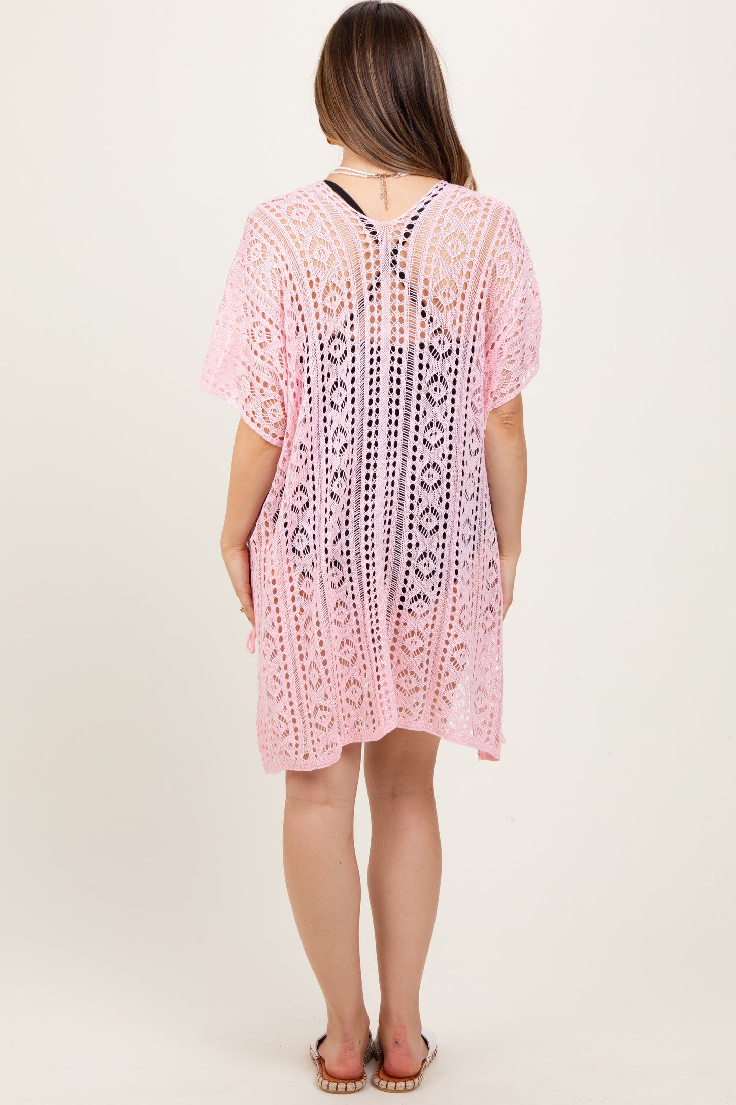 woman wearing a pink lace maternity cover-up with a loose fit and short sleeves, showing a hint of a baby bump