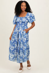 woman wearing a blue floral maxi dress with puff sleeves and pockets