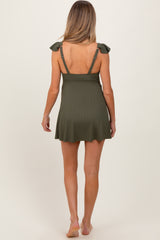 woman wearing a dark green maternity swim dress with ruffled shoulder straps, showing the back view