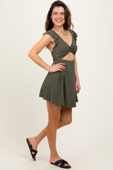 woman wearing an olive green ribbed mini dress with ruffle sleeves and a cutout design, posing with one hand on her hip