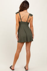 woman wearing an olive green tie-back skater dress with a flared skirt and decorative shoulder bows