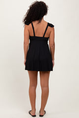 woman wearing a black ribbed skater dress with tie shoulder straps, shown from the back