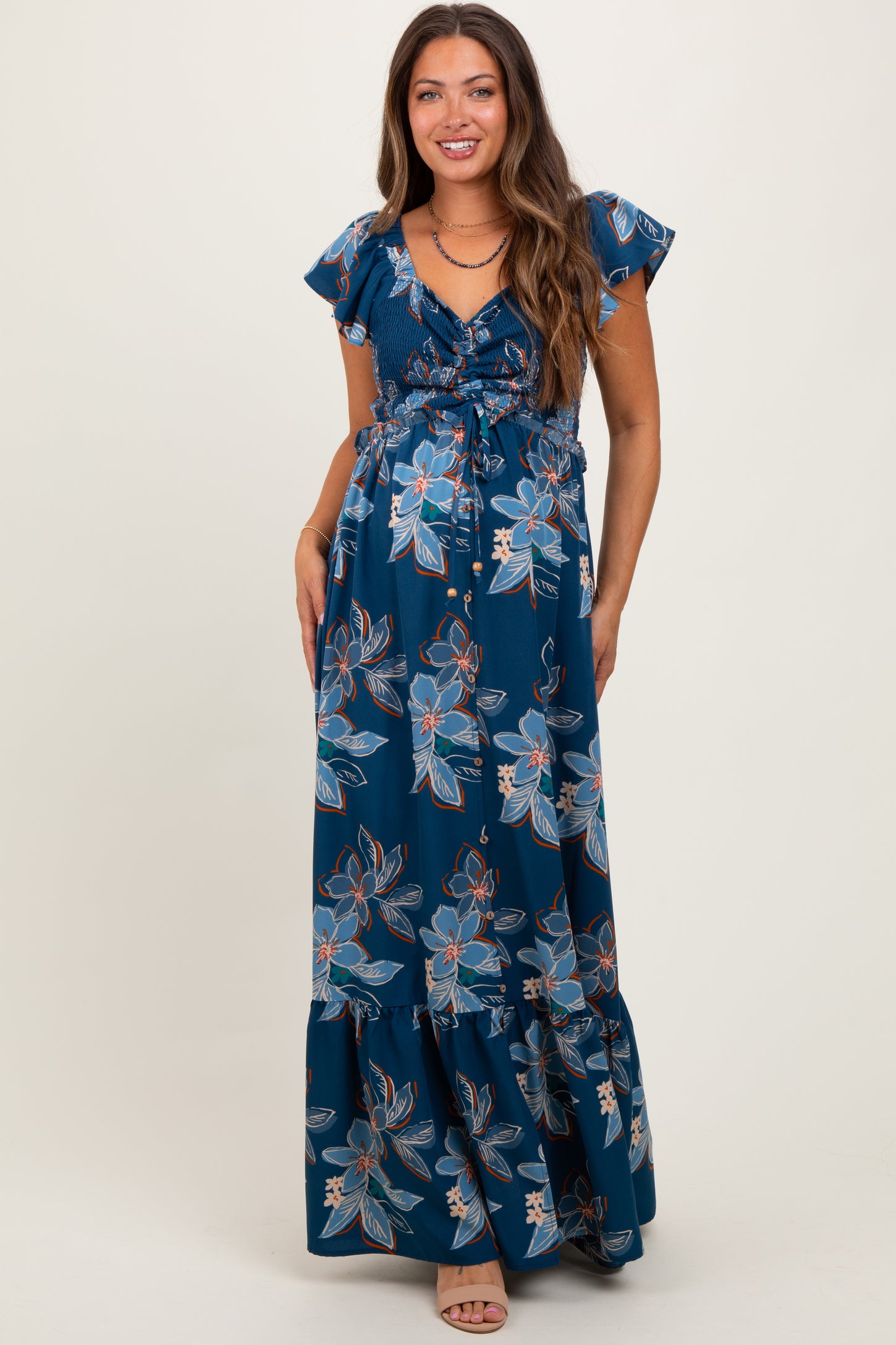 woman wearing a navy blue floral maternity maxi dress with short sleeves and a tie waist, showing her baby bump