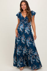 woman wearing a floral print navy blue maternity maxi dress with short flutter sleeves and a tie front detail