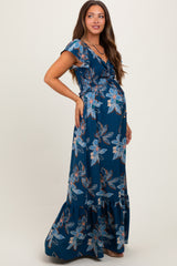 woman wearing a dark blue floral maternity maxi dress with a ruffled hem and a visible baby bump