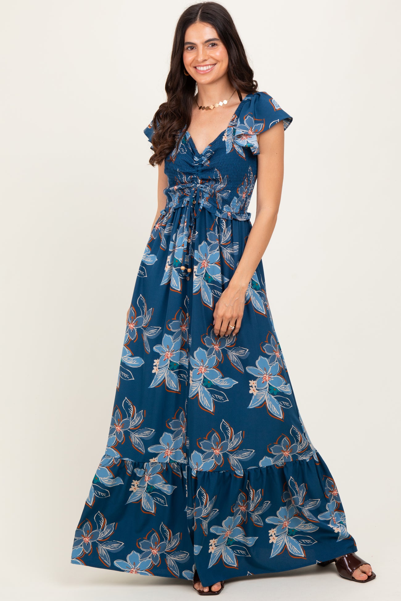 woman wearing a navy blue floral maxi dress with a v-neckline and tie waist detail