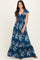woman wearing a navy blue floral maxi dress with a v-neckline and tie waist detail