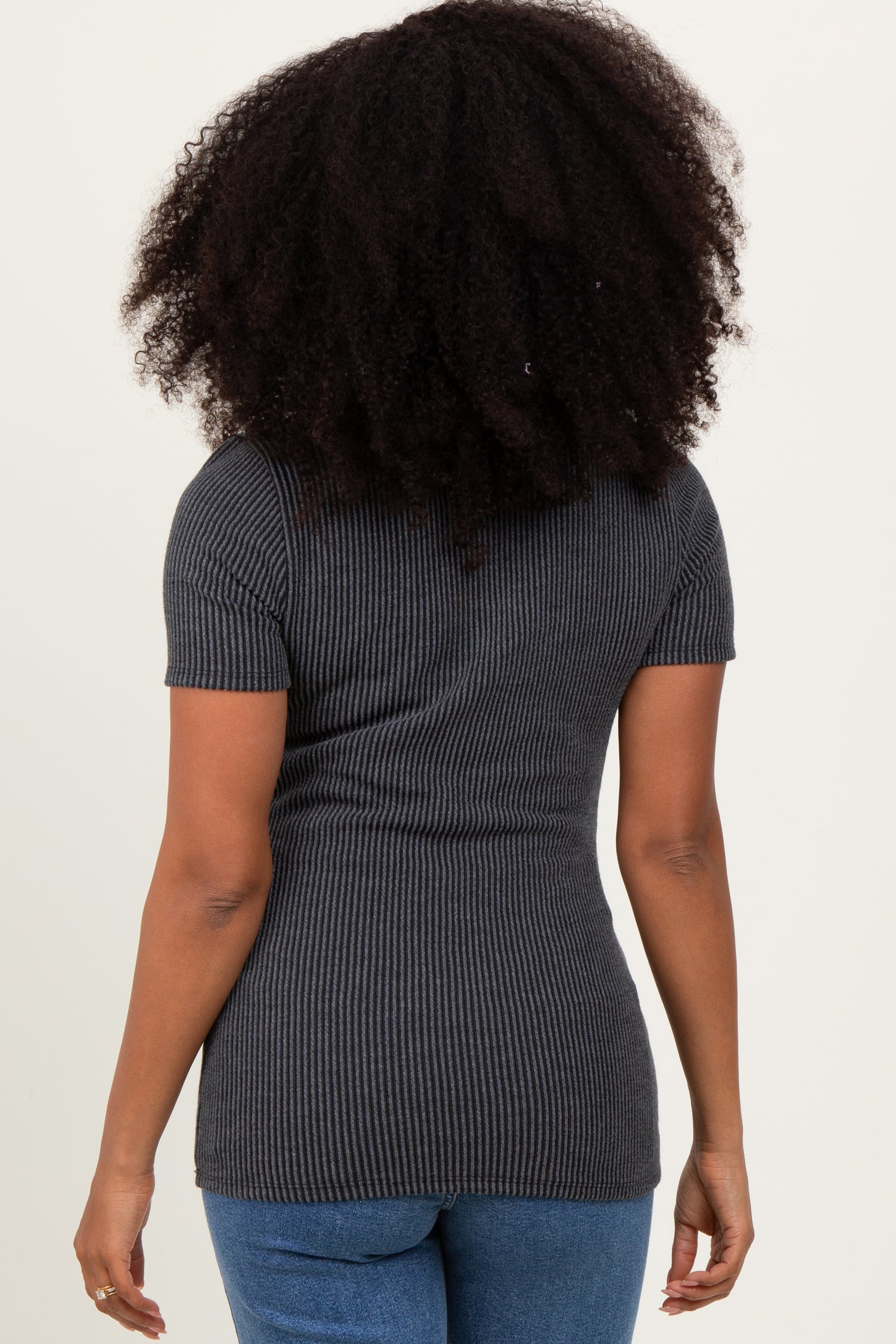 woman wearing a charcoal gray ribbed short sleeve top and blue jeans, seen from the back