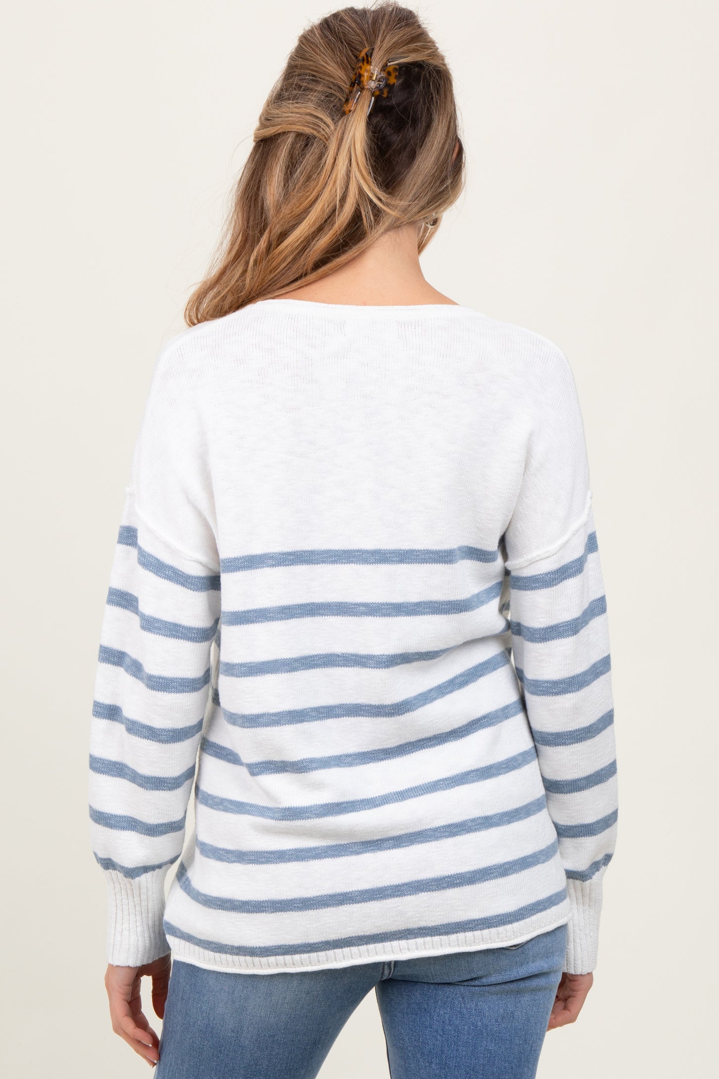 woman wearing a white and blue striped maternity sweater with long sleeves seen from the back