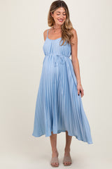 woman wearing a light blue pleated maternity dress with adjustable straps and a tie waist, showcasing her baby bump