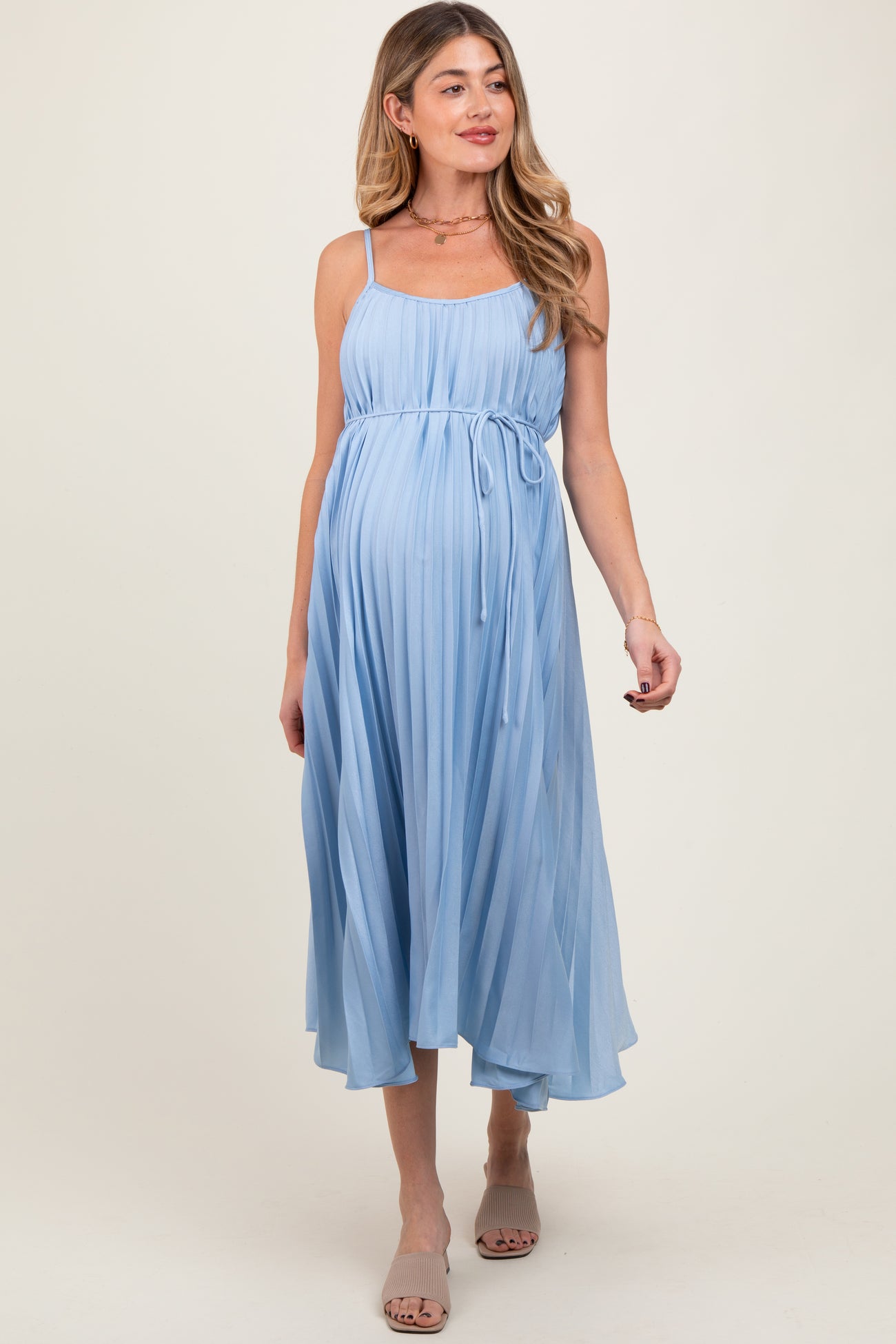 woman wearing a light blue pleated maternity dress with a tie waist and a visible baby bump