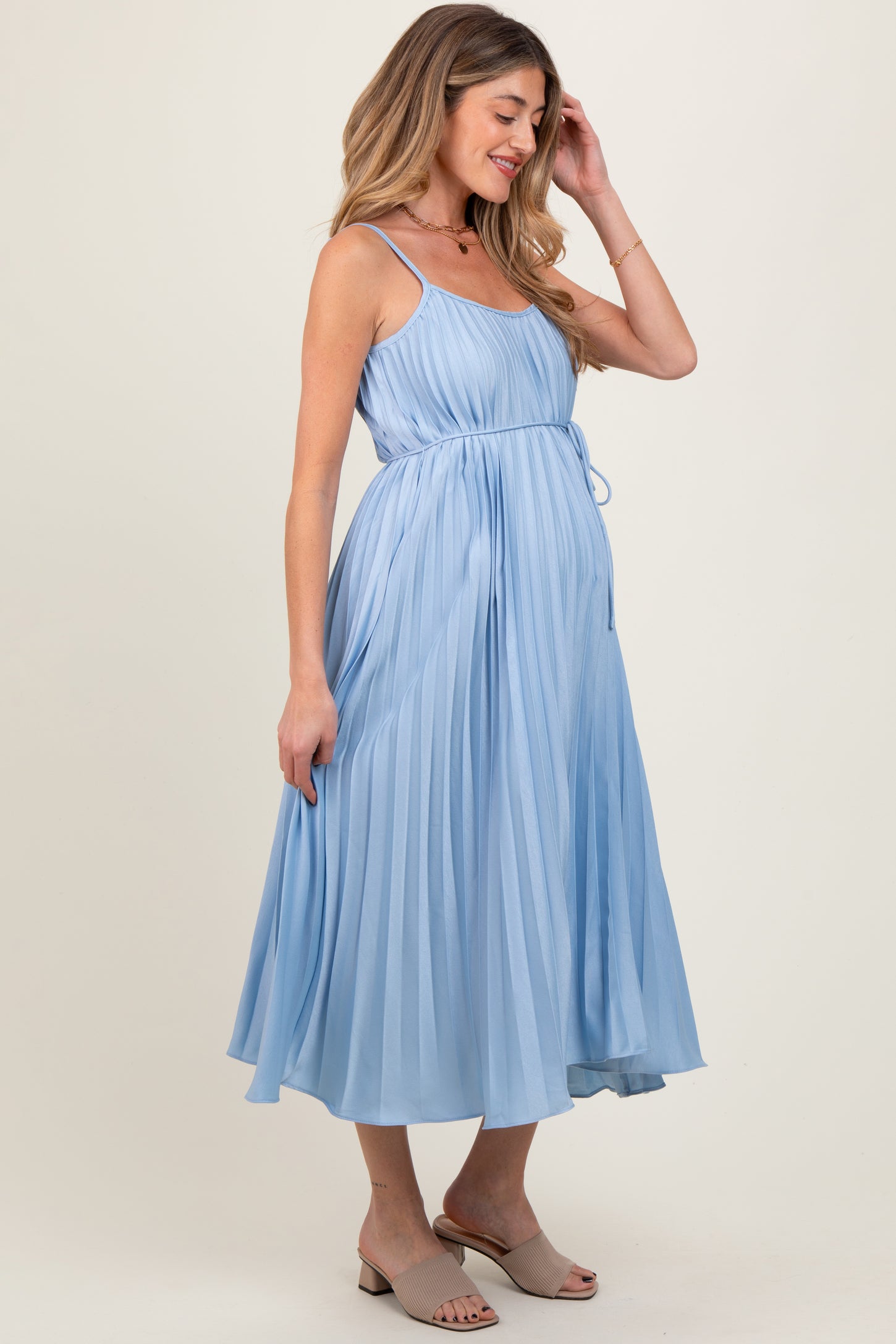 woman wearing a light blue pleated maternity dress with adjustable tie waist and a visible baby bump
