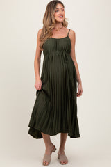 woman wearing an olive green pleated maternity dress with a tie waist and adjustable spaghetti straps