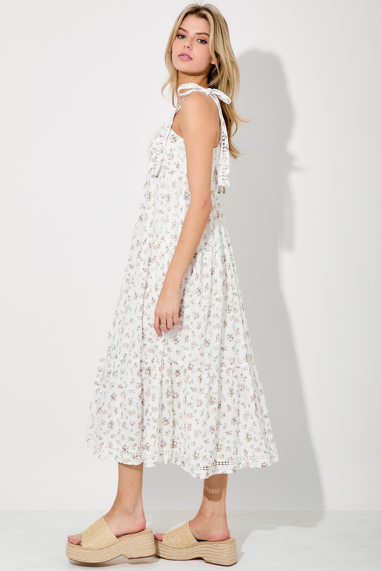 woman wearing a white floral midi dress with tie straps and tan platform sandals