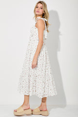 woman wearing a white floral midi dress with tie straps and tan platform sandals