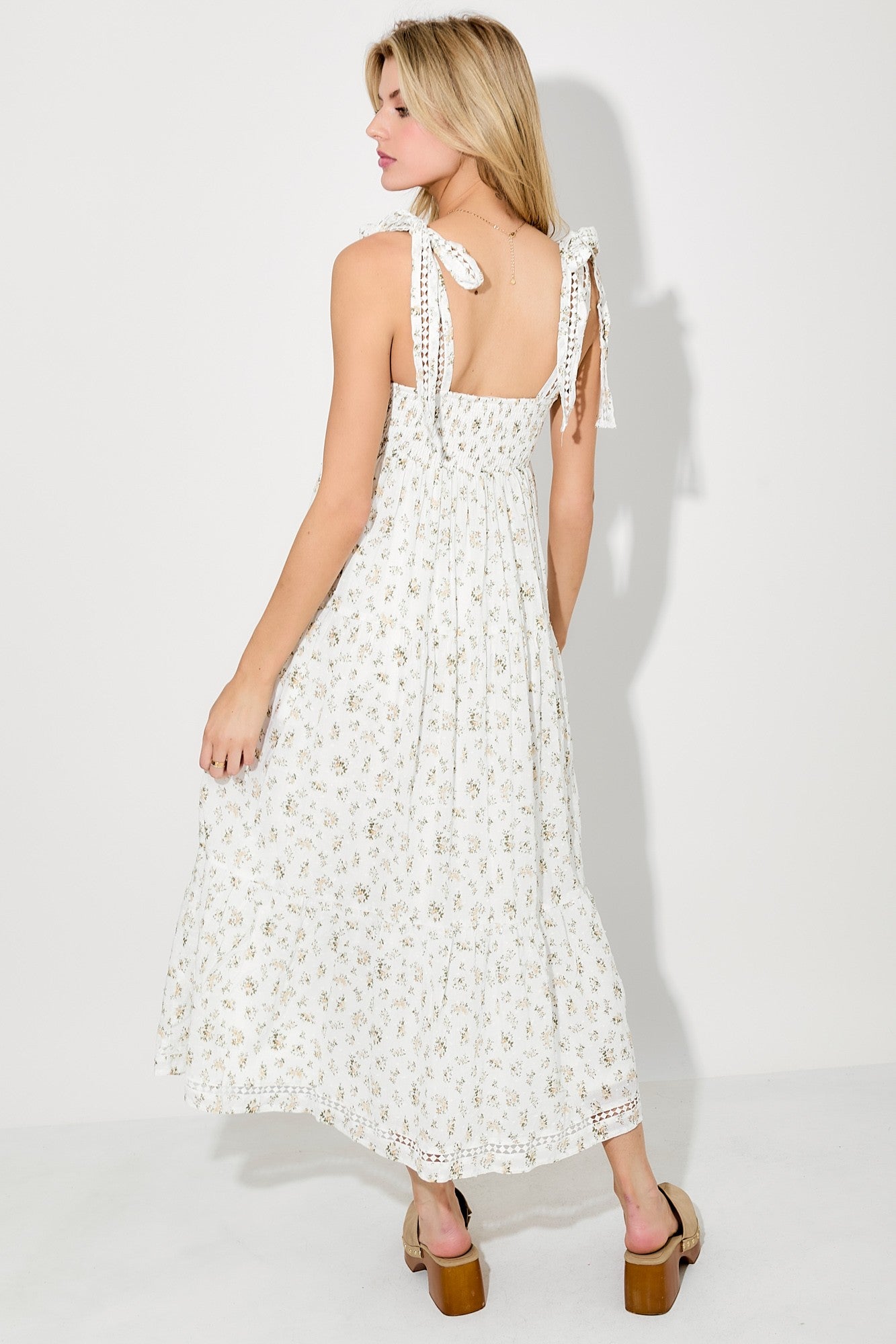 woman wearing a white floral maxi dress with adjustable tie straps and a keyhole back detail