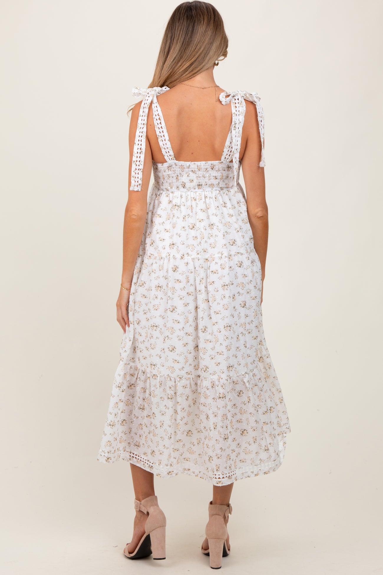 woman wearing a white floral print maternity dress with tie shoulder straps and a tiered hem