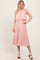woman wearing a light pink pleated midi dress with a halter neck and layered top, standing in a neutral background