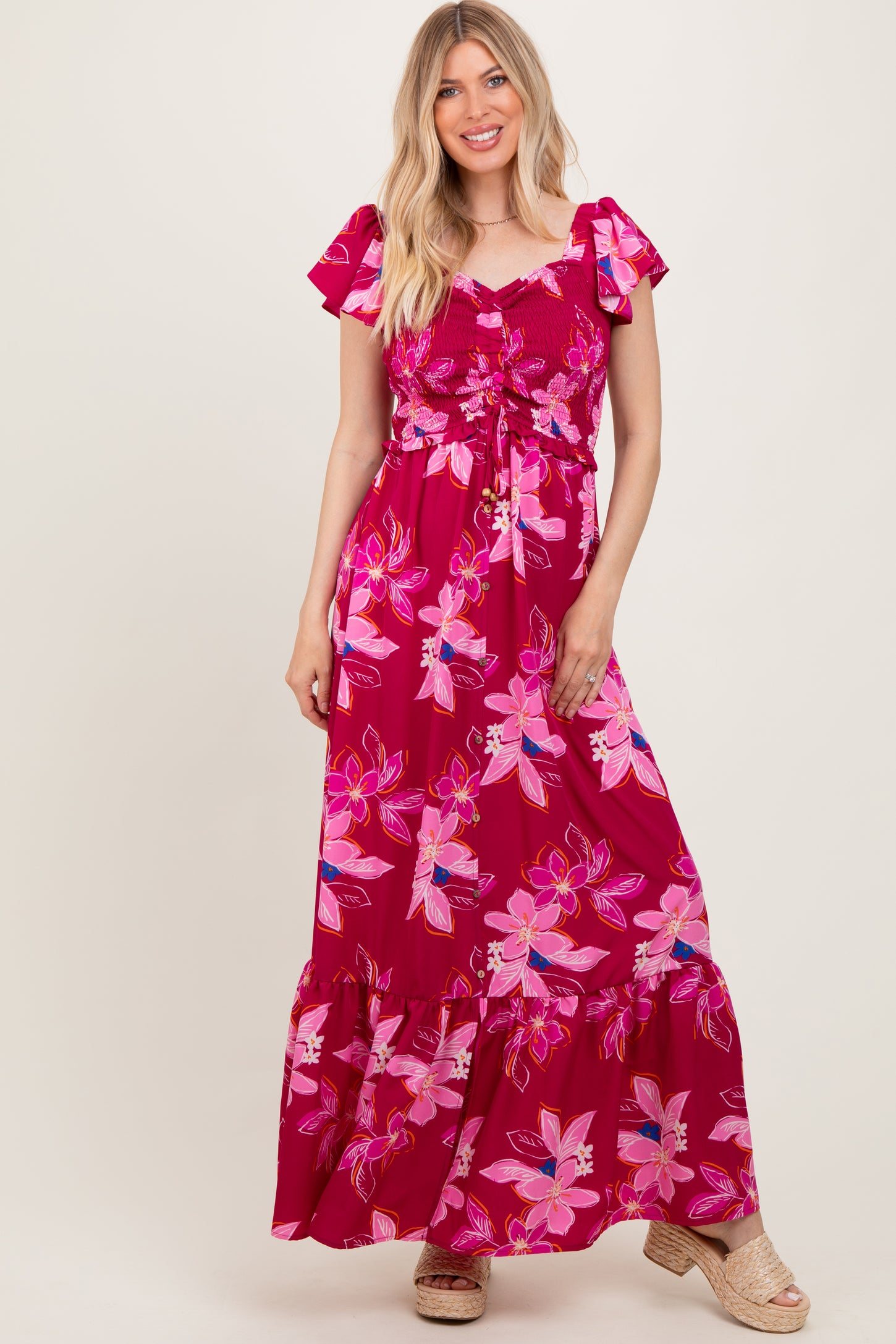 woman wearing a pink floral maxi dress with ruffled sleeves and a ruched bodice