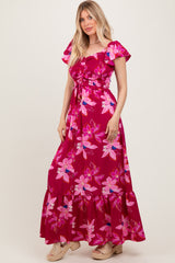 woman wearing a fuchsia floral maxi dress with short puff sleeves and a tie waist