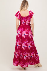 woman wearing a pink floral maxi dress with ruffled sleeves and a tie waist, shown from the back