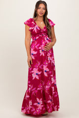 woman wearing a floral pink maternity maxi dress with flutter sleeves and a tie front, showing her baby bump