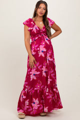 woman wearing a pink floral maternity maxi dress with flutter sleeves and a tie front, showing her baby bump