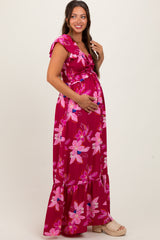 woman wearing a fuchsia floral print maternity maxi dress and holding her baby bump