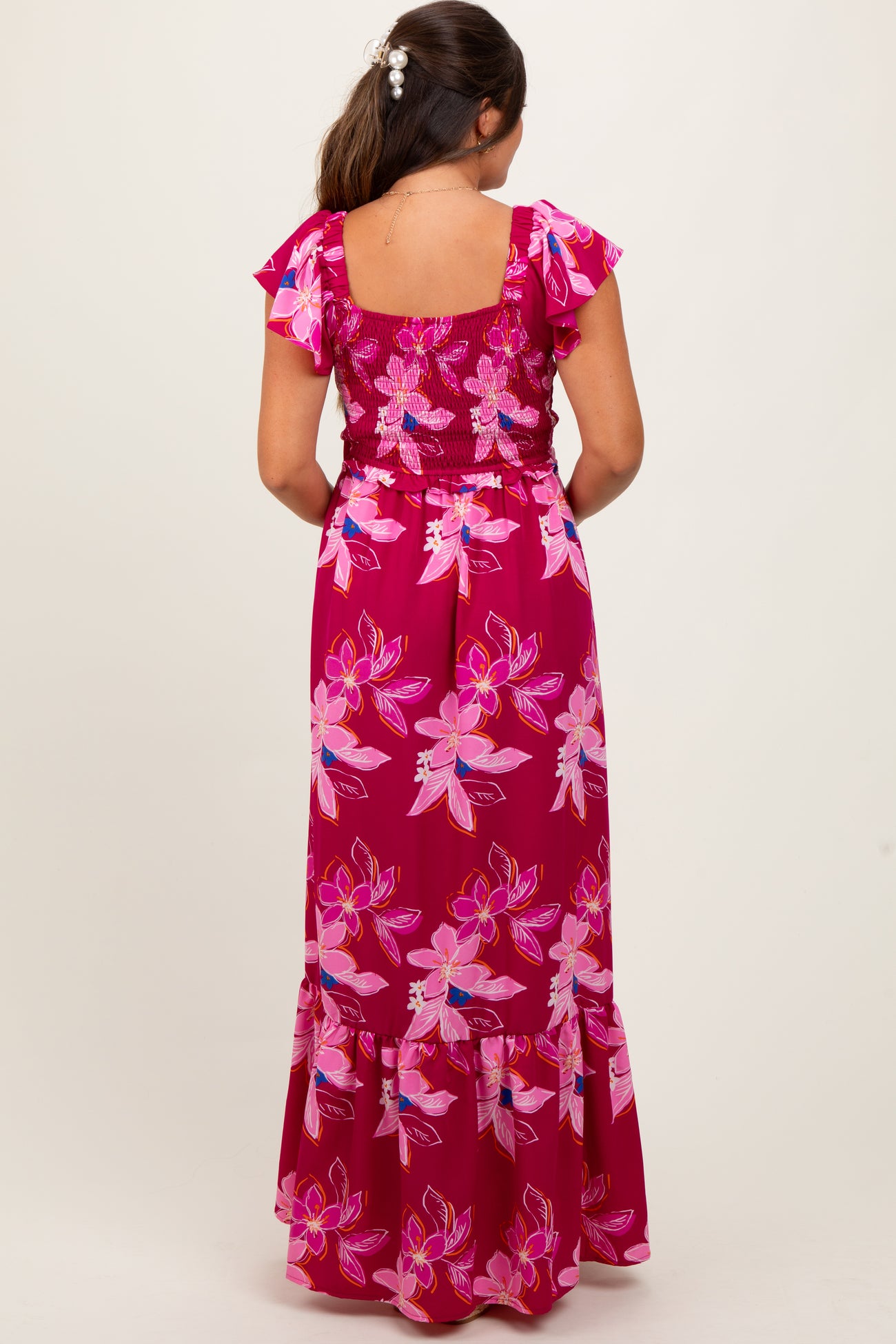 woman wearing a floral print pink maternity maxi dress with short ruffled sleeves and a smocked bodice, showing baby bump