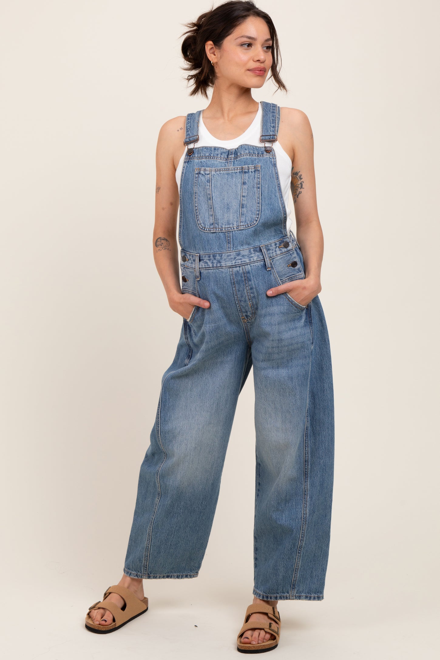 woman wearing a light blue denim maternity overall with wide legs and pockets