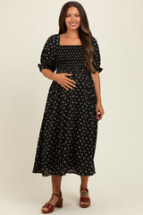woman wearing a black floral maternity dress with smocked bodice and puff sleeves, showcasing her baby bump