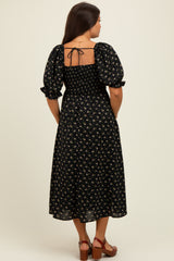 woman wearing a black floral maternity dress with puff sleeves and a smocked back, showing a baby bump