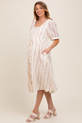 woman wearing a light pink floral maternity dress with a scoop neckline and cinched waist, showing her baby bump